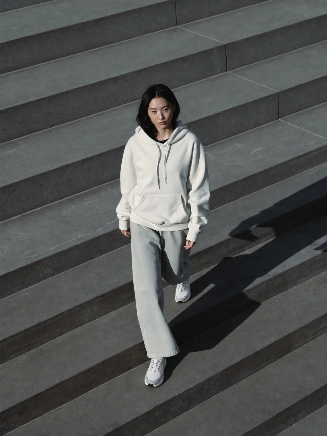 Walking down wide stone steps in a cream hoodie
