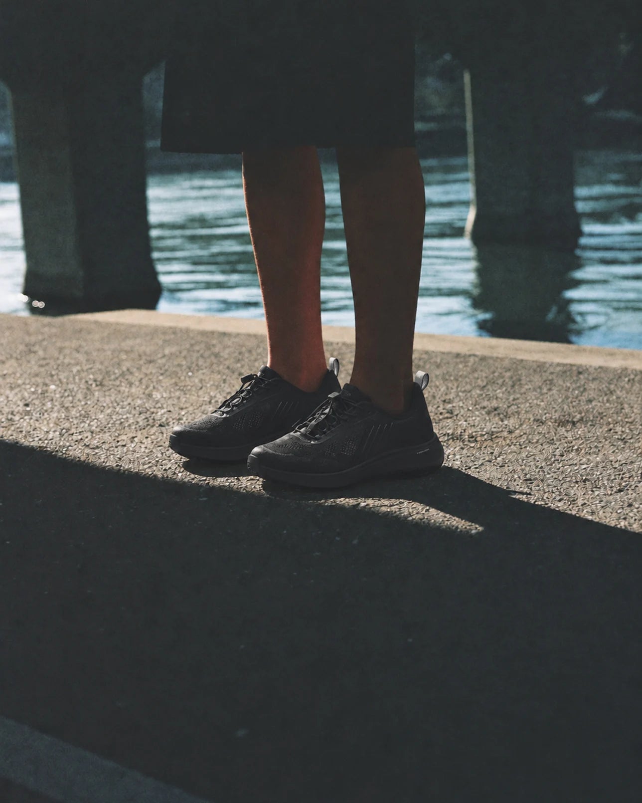 Standing in black BR-001 by the Han River, under a bridge