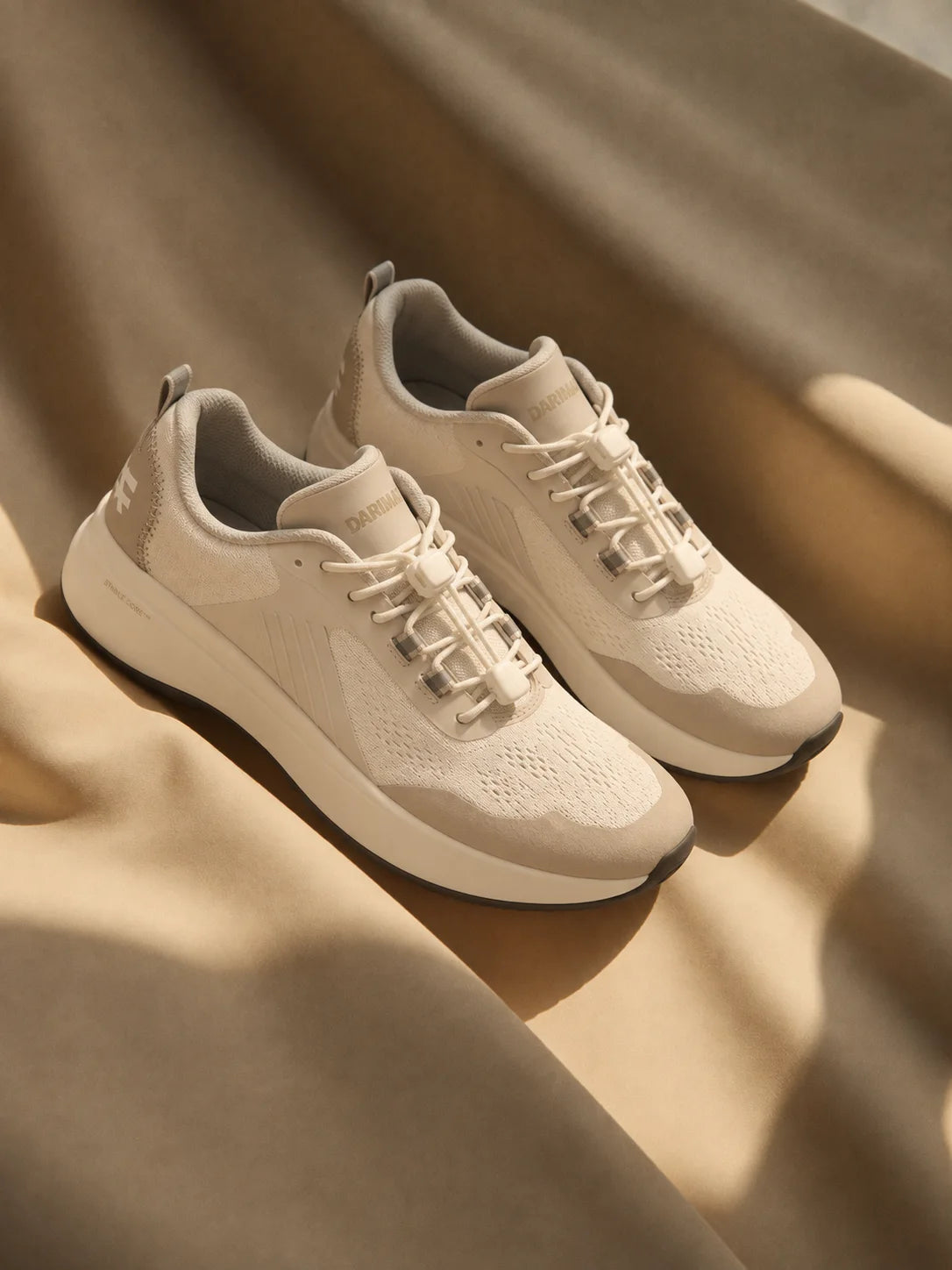 A pair of light trainers resting on draped fabric