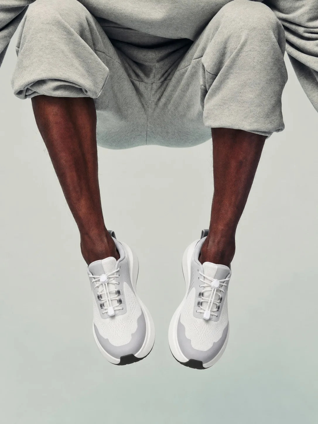 Mid-jump in white trainers, studio