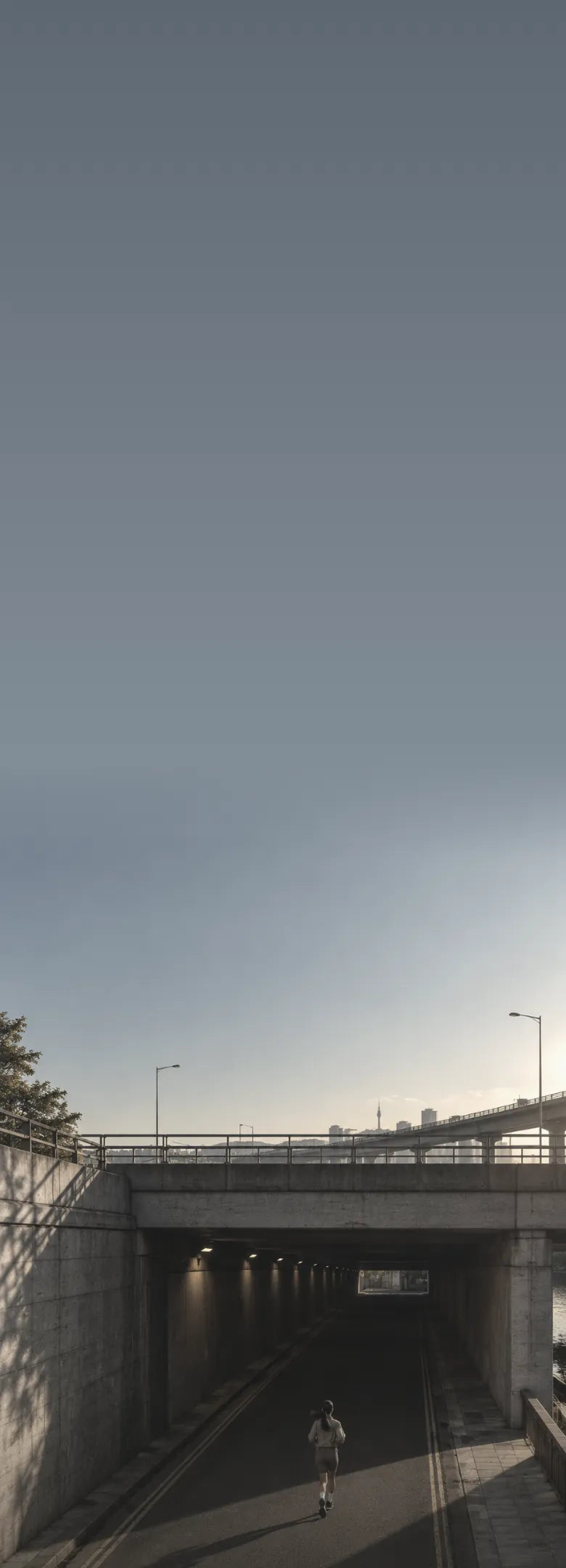 Runner heading into an underpass by the river in Seoul at golden hour