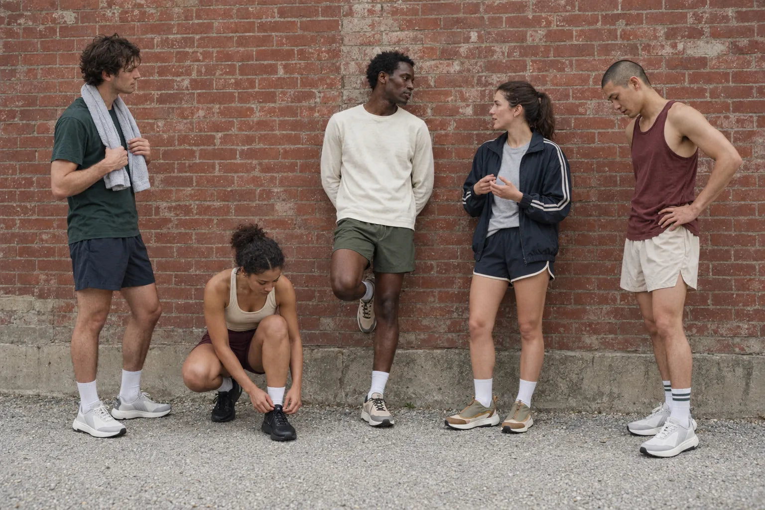 Five people in DARIMATI shoes against a brick wall, between workouts