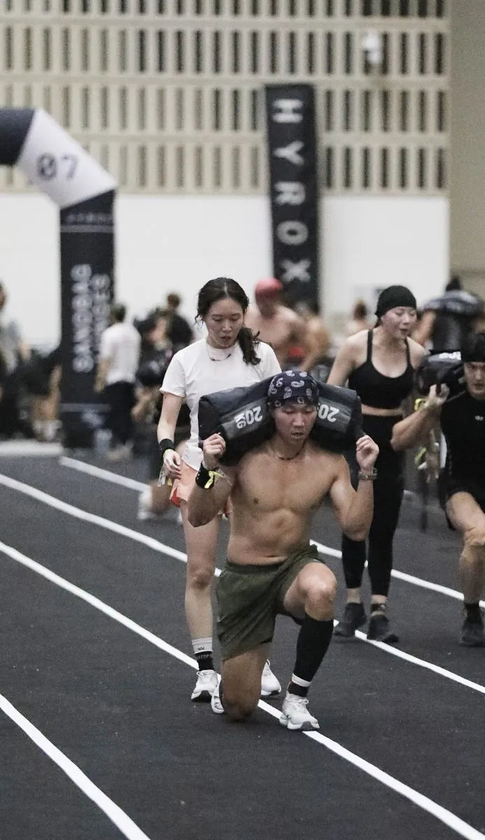 Coach Lee Sang-hak carrying a sandbag at a HYROX race